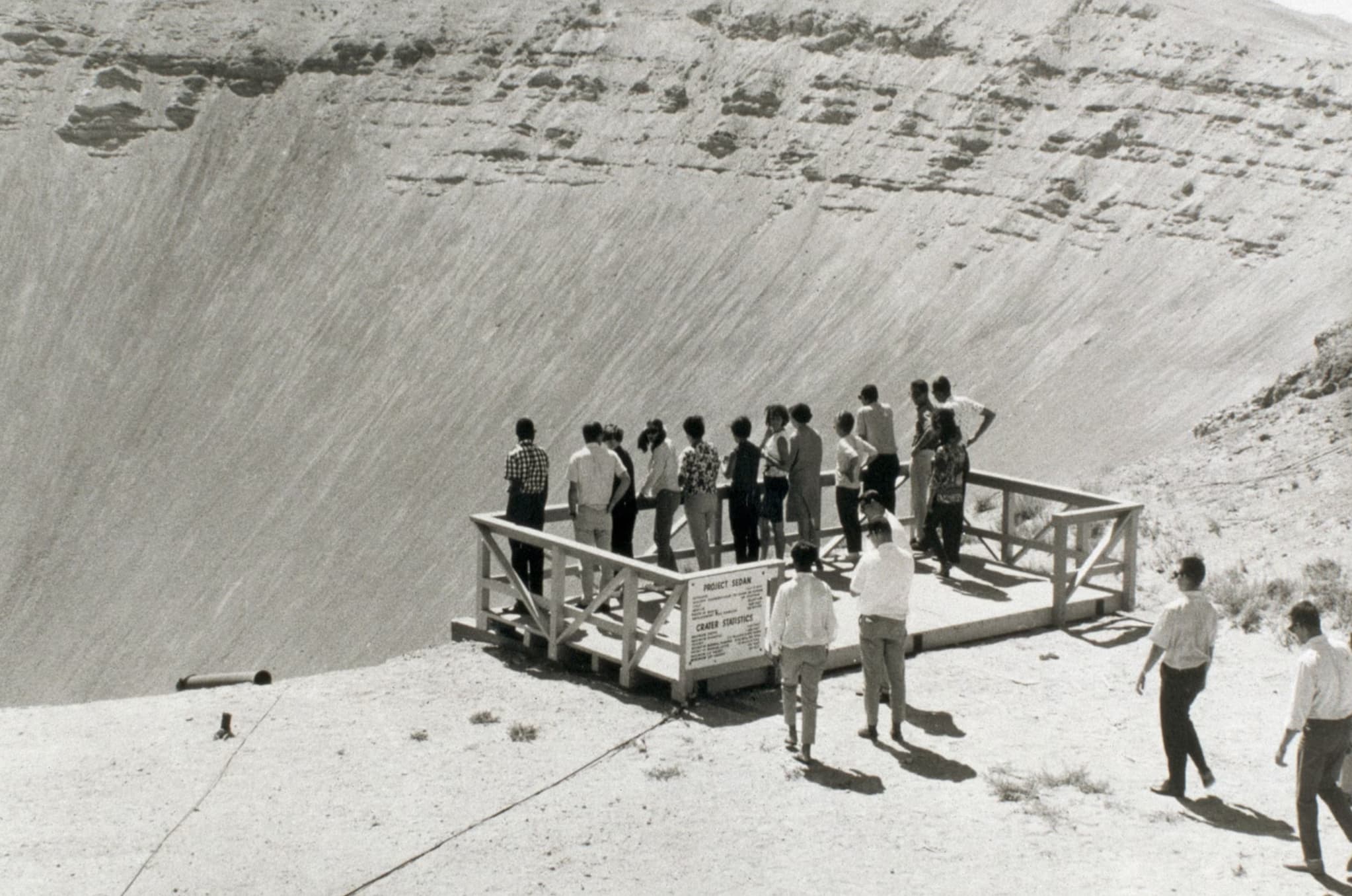 Tourists look down upon a crater from a past nuclear test, 1962. 